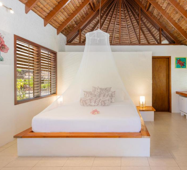 Bedroom with a canopy bed in a tropical-style room. Wander Beyond Co accommodation for Women's Group Trips